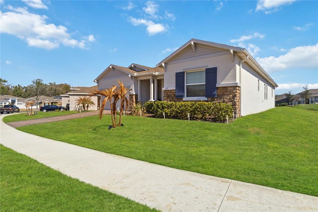 A single-story house with a stone facade, blue shutters, and a paved driveway — 4409 EASTMINSTER ROAD, DAVENPORT, FL