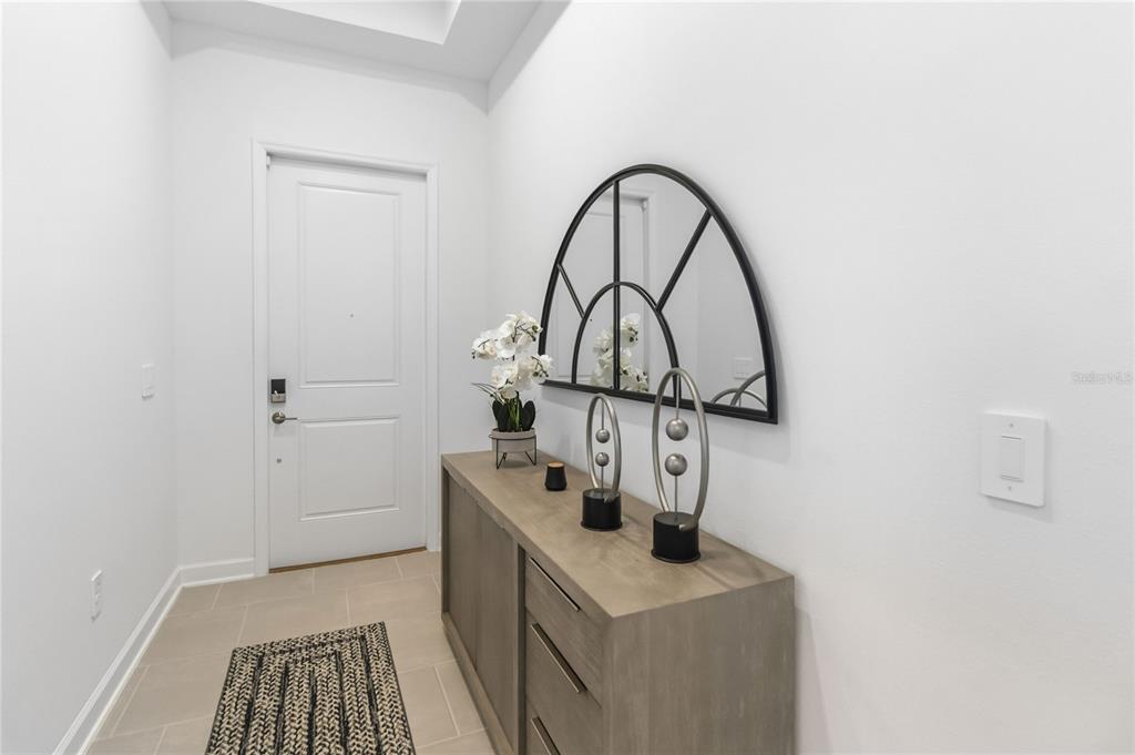 A modern entryway features a wooden console table, a decorative arched mirror, and tile flooring — 4409 EASTMINSTER ROAD, DAVENPORT, FL