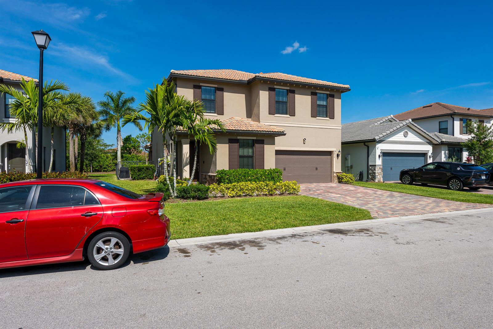 A two-story suburban house with a tan stucco exterior, brown shutters, and a paved driveway — 4819 Chantilly Road, Lake Worth FL 33467, LAKE WORTH, FL