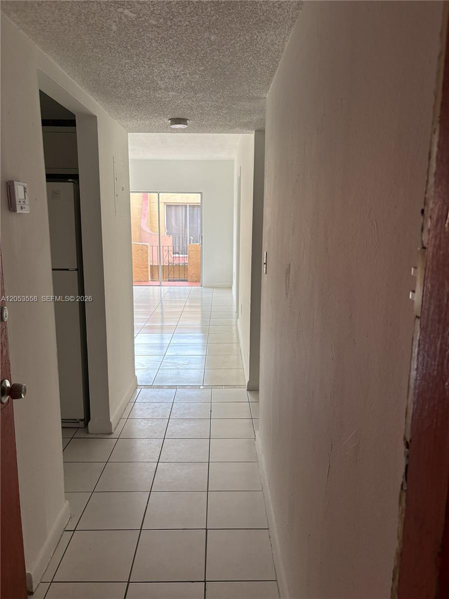 A tiled hallway leads to a living area with a sliding glass door to a balcony — 3675 W 11th Ave # 319, Hialeah FL 33012, HIALEAH, FL