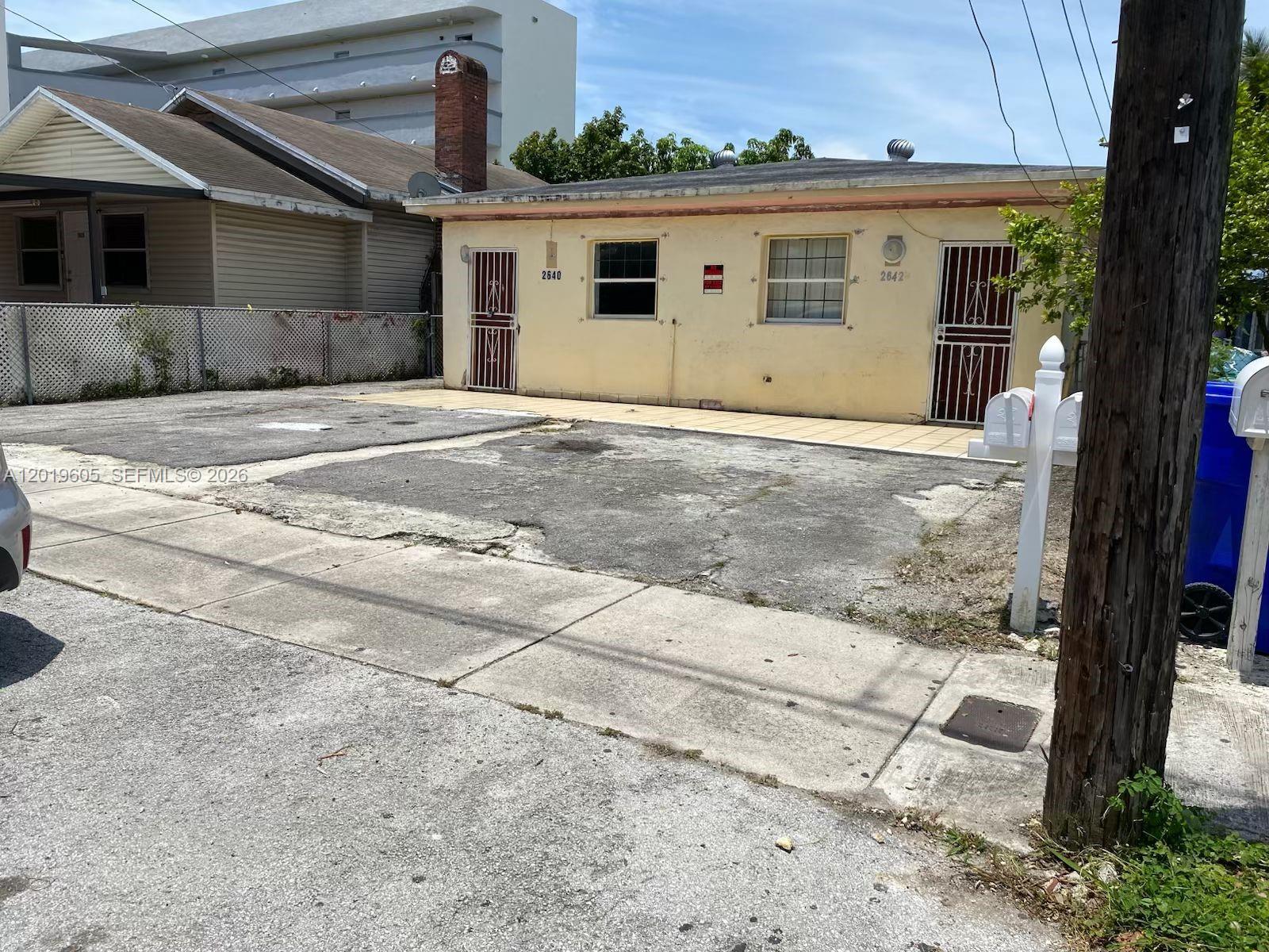 A single-story duplex with a concrete driveway and two front doors with security gates — 2640 NW 23rd Ct, Miami FL 33142, MIAMI, FL