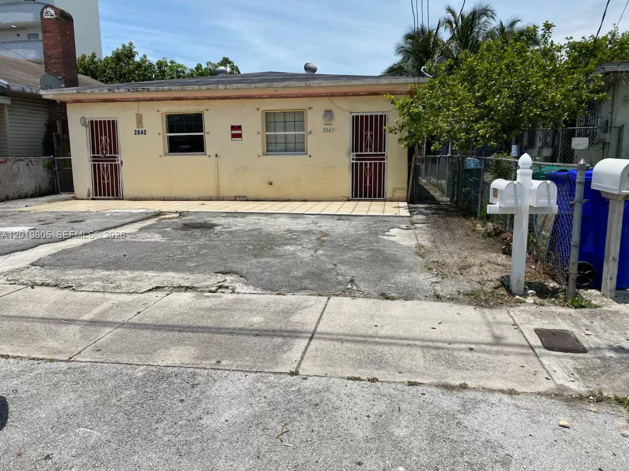 A single-story duplex with a concrete driveway and two front doors with security gates — 2640 NW 23rd Ct, Miami FL 33142, MIAMI, FL