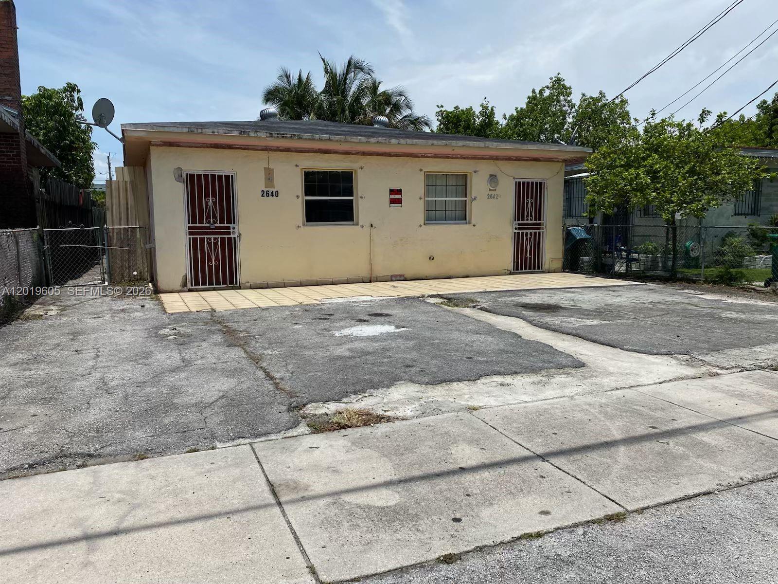 A single-story duplex with a paved parking area and two front entrances — 2640 NW 23rd Ct, Miami FL 33142, MIAMI, FL