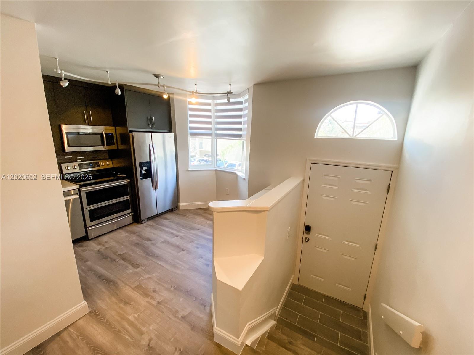 A kitchen with stainless steel appliances and dark cabinetry overlooks a tiled entryway — 8661 NW 4th Ter # 903, Miami FL 33126, MIAMI, FL