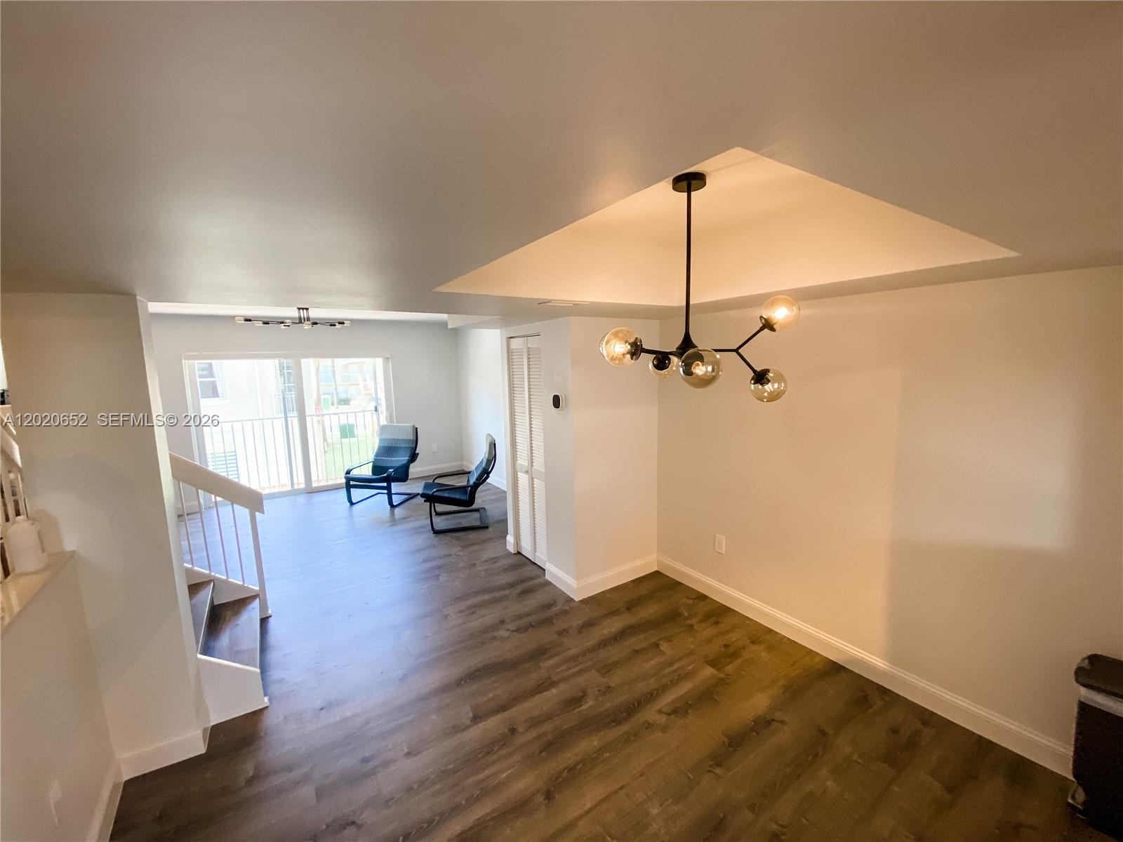 An open living area features wood-look flooring, a modern chandelier, and a staircase — 8661 NW 4th Ter # 903, Miami FL 33126, MIAMI, FL