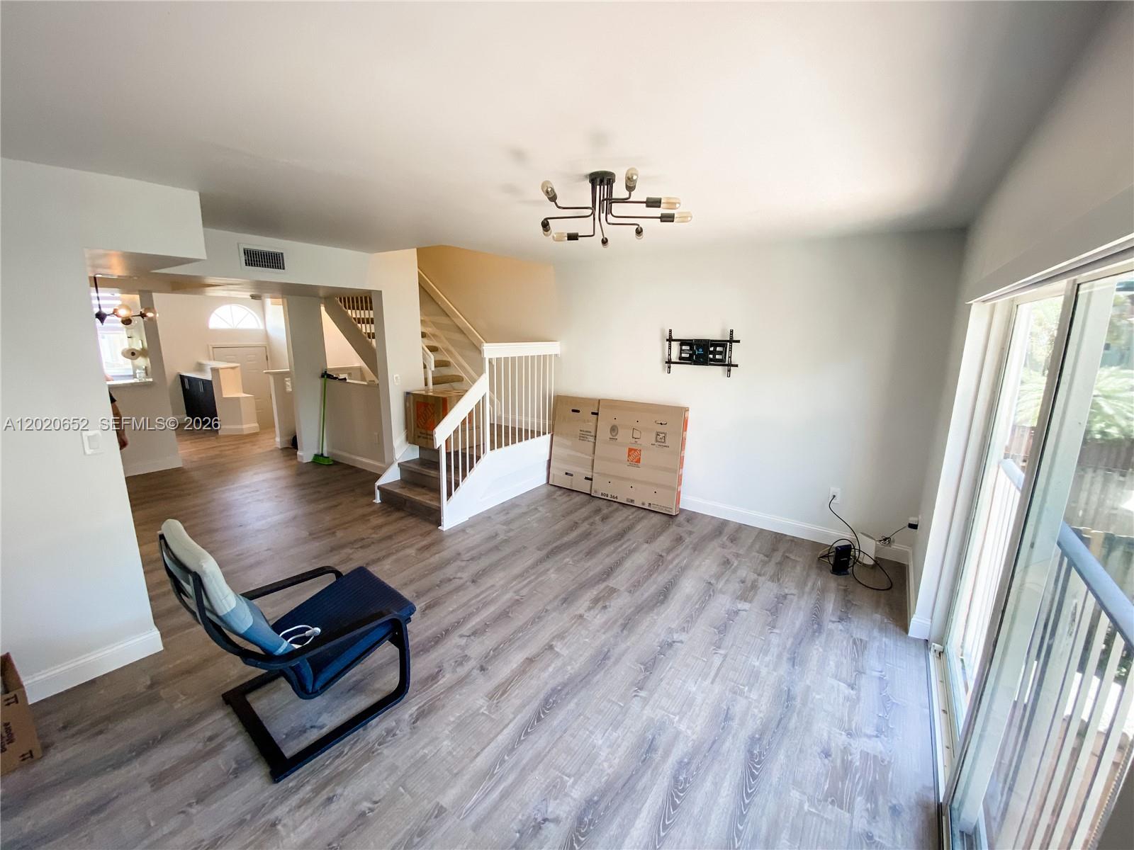 An open living room features wood-look flooring, a staircase, and a modern light fixture — 8661 NW 4th Ter # 903, Miami FL 33126, MIAMI, FL