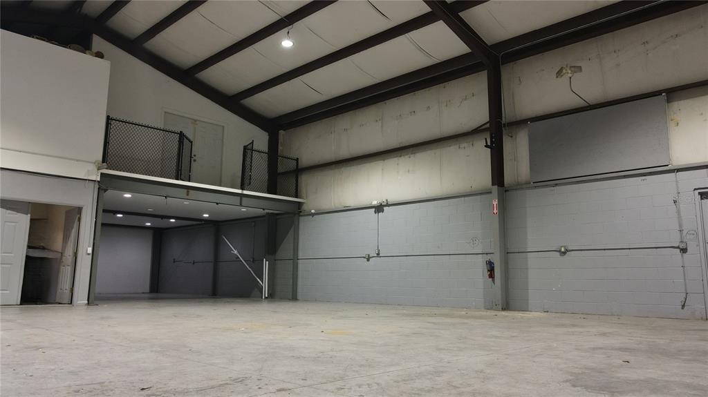 A large, open warehouse space features a concrete floor, high ceilings, and a mezzanine level — 3710 NE 47TH PLACE, OCALA, FL