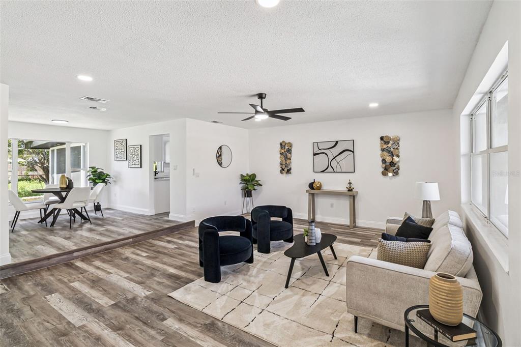 A living room with wood-look flooring, a sunken dining area, and neutral-toned furniture — 903 JEFFERSON ROAD, ROCKLEDGE, FL