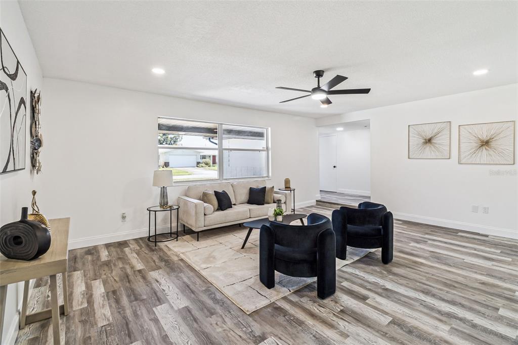 A living room features light wood-look flooring, a beige sofa, and two dark blue armchairs — 903 JEFFERSON ROAD, ROCKLEDGE, FL