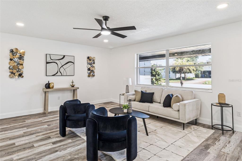 A living room features a beige sofa, two dark blue armchairs, and wood-look flooring — 903 JEFFERSON ROAD, ROCKLEDGE, FL