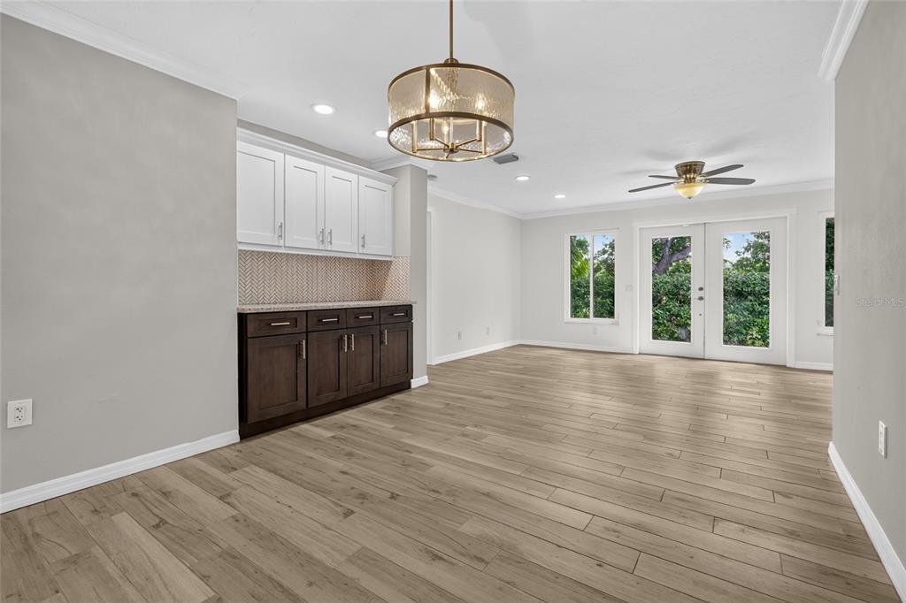 A dining room with wood-look floors, a wet bar, and French doors leading outside — 2129 LINWOOD DRIVE, SARASOTA, FL
