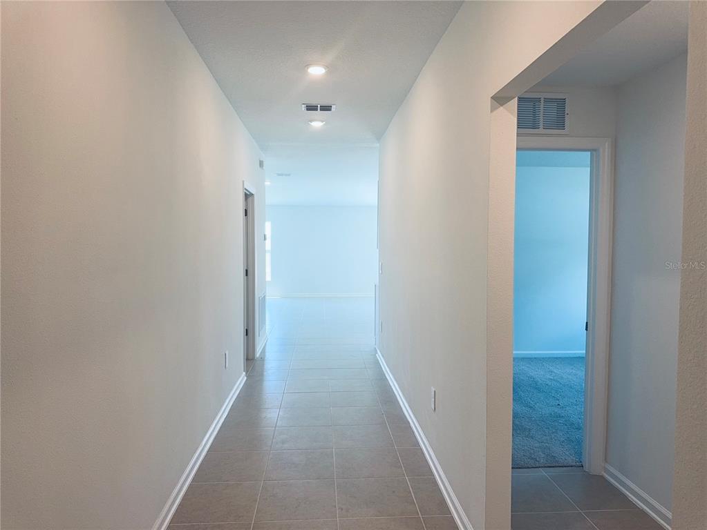 A hallway with tile flooring leads to an open living area with a side bedroom — 2362 MCKINLEY DRIVE, LAKE WALES, FL