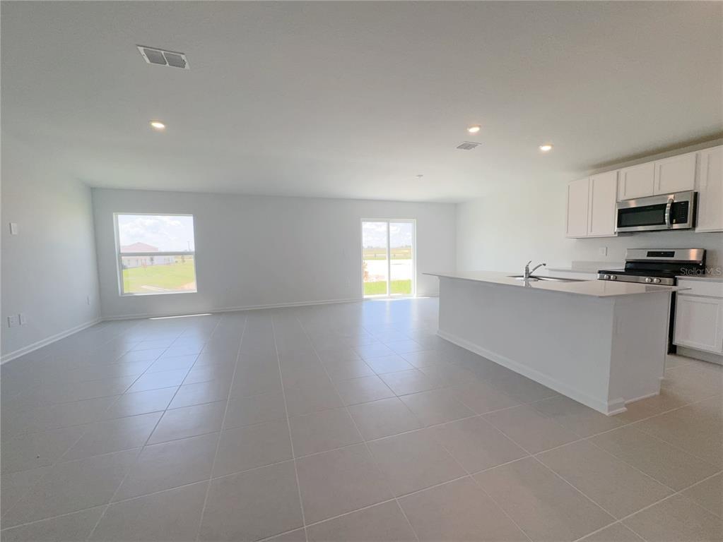 An open-concept kitchen and living area featuring white cabinets, a kitchen island, and tile flooring — 2362 MCKINLEY DRIVE, LAKE WALES, FL