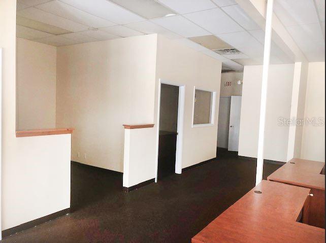 An office interior features beige walls, dark carpeting, a drop ceiling, and wooden desk surfaces — 9701 N 66TH STREET, PINELLAS PARK, FL