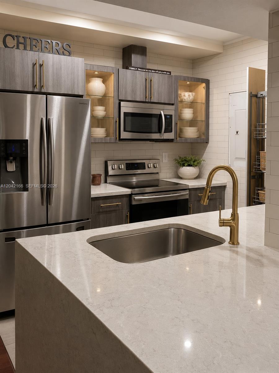 A modern kitchen features stainless steel appliances, dark wood cabinetry, and a quartz-topped island — PEMBROKE PINES, FL