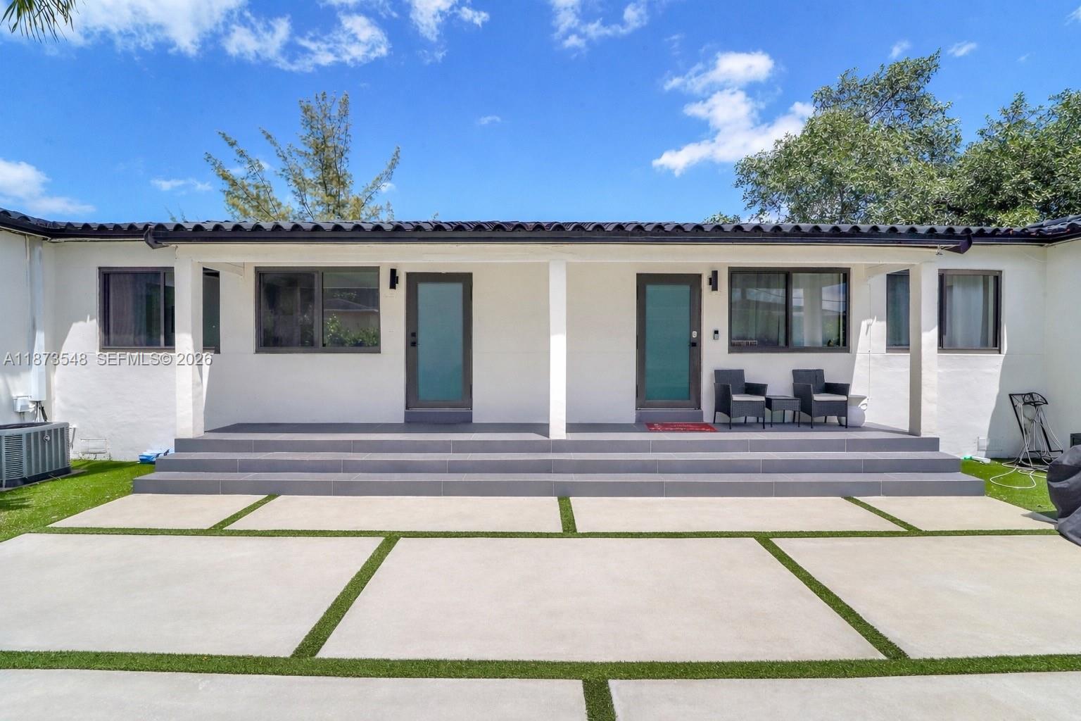 The exterior of a white house features a tiled patio, two glass doors, and concrete pavers — 621 SW 33RD AVENUE, Miami FL 33135, MIAMI, FL