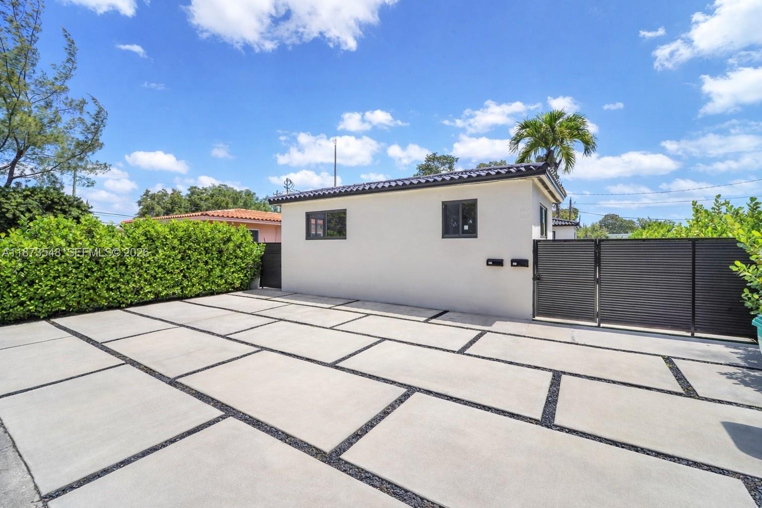 A paved driveway leads to a white exterior building with a dark gate and fence — 621 SW 33RD AVENUE, Miami FL 33135, MIAMI, FL