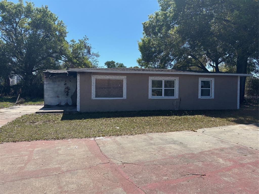 A single-story house with a boarded-up window and fire-damaged exterior wall — 403 MERCADO AVENUE, ORLANDO, FL
