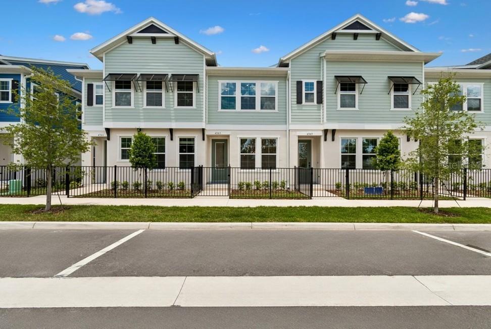 A row of light green townhomes with black metal fencing and small front yards — 4365 ROUSH AVENUE, ORLANDO, FL
