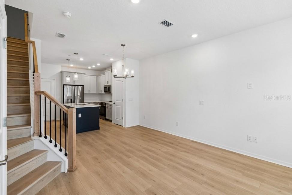 An open-concept living area features light wood flooring, a staircase, and a modern kitchen — 4365 ROUSH AVENUE, ORLANDO, FL