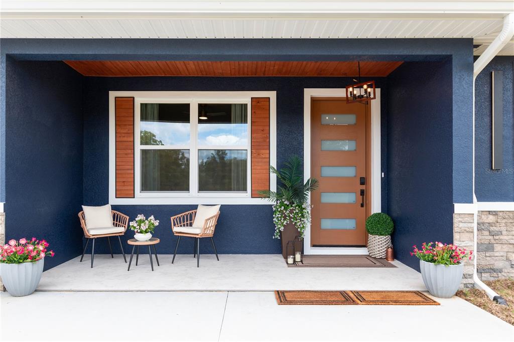 A blue single-story house with a metal roof, stone accents, and a wooden garage door — 6254 W PEKING COURT, DUNNELLON, FL