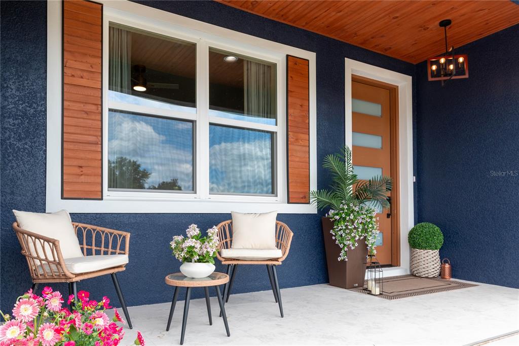 A covered front porch features a dark blue exterior, a wood-toned door, and two chairs — 6254 W PEKING COURT, DUNNELLON, FL