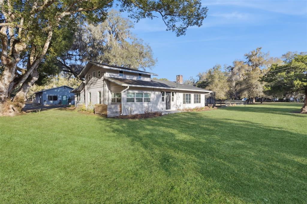 A light-colored, two-story house with a large lawn and mature trees in the background — 43411 STATE ROAD 19, ALTOONA, FL