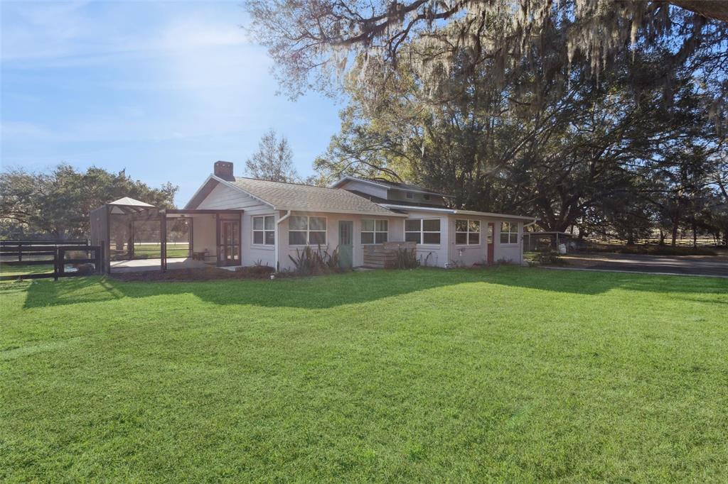 A single-story house with a screened patio sits on a large lawn under oak trees — 43411 STATE ROAD 19, ALTOONA, FL