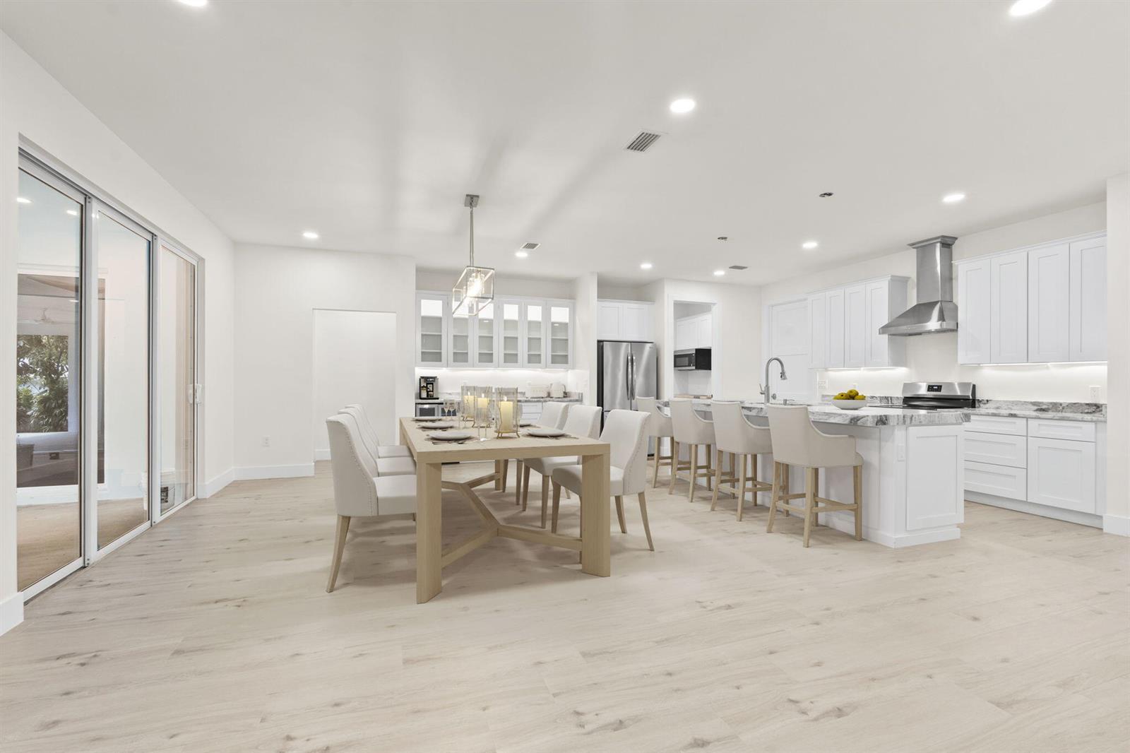 A bright, open-concept kitchen and dining area features white cabinetry, marble countertops, and light flooring — 516 SE Alamanda Way, Stuart FL 34996, STUART, FL