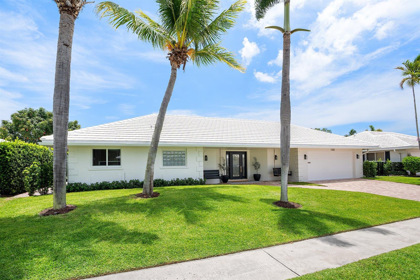 A white single-story house with a tiled roof, palm trees, and a paved driveway — 1332 SW Tamarind Way, Boca Raton FL 33486, BOCA RATON, FL