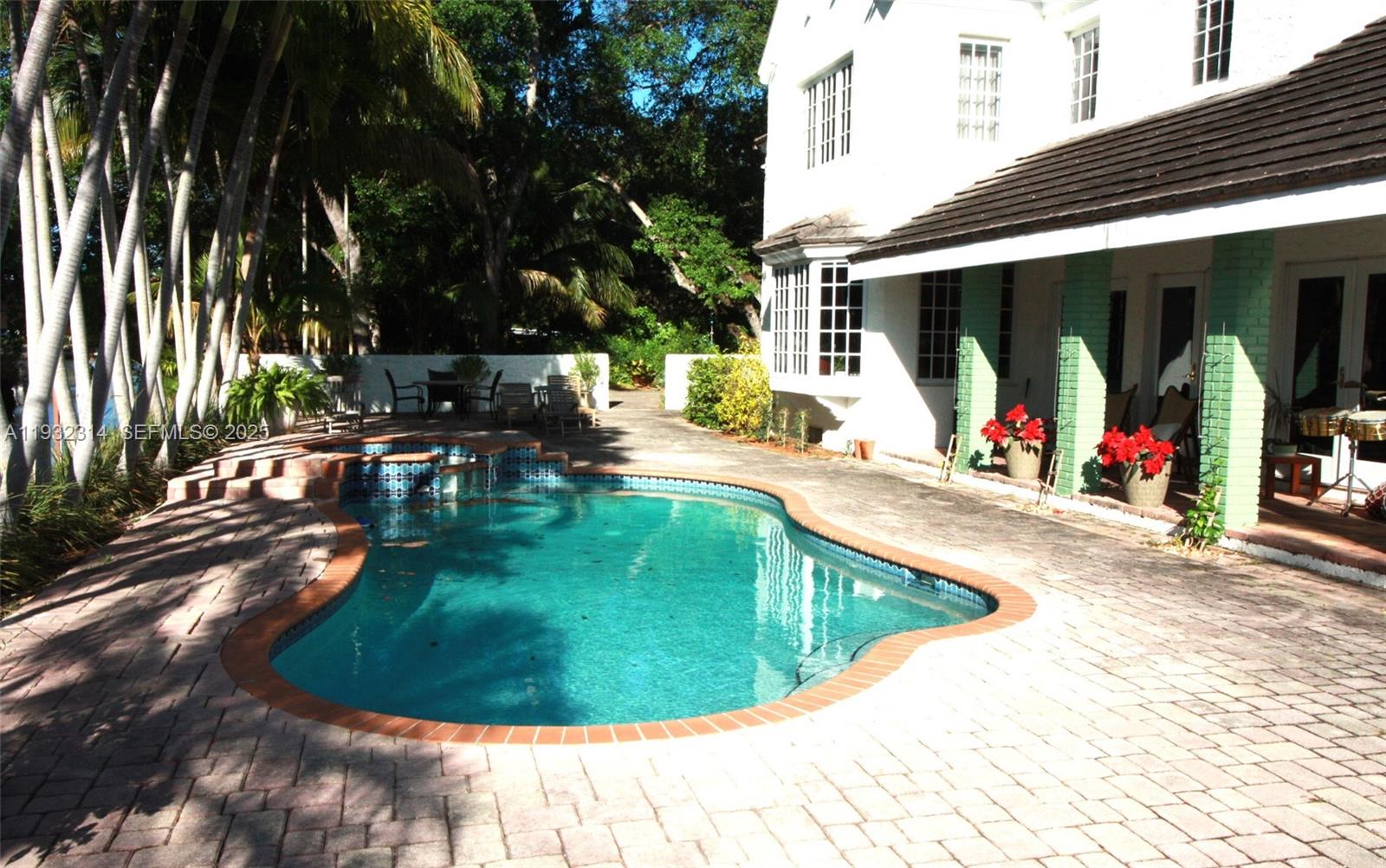 A backyard features a swimming pool with a spa, brick patio, and a white house — 6750 Granada Blvd, Coral Gables FL 33146, CORAL GABLES, FL