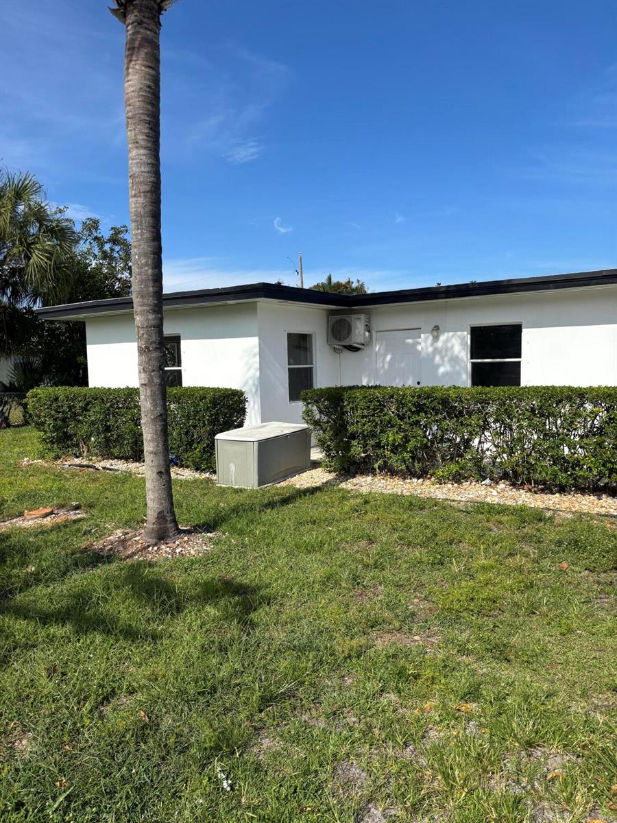 A white exterior wall features a door, windows, an air conditioning unit, and a generator — 328 Urquhart Street, FL 33461, FL