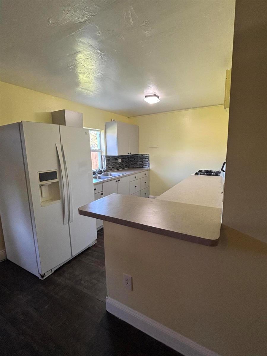 A kitchen features white cabinets, a side-by-side refrigerator, a peninsula counter, and light-colored walls — 328 Urquhart Street, FL 33461, FL