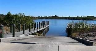 A concrete boat ramp leads into a lake next to a wooden pier — 10441 VAN WYCK TERRACE, PORT CHARLOTTE, FL