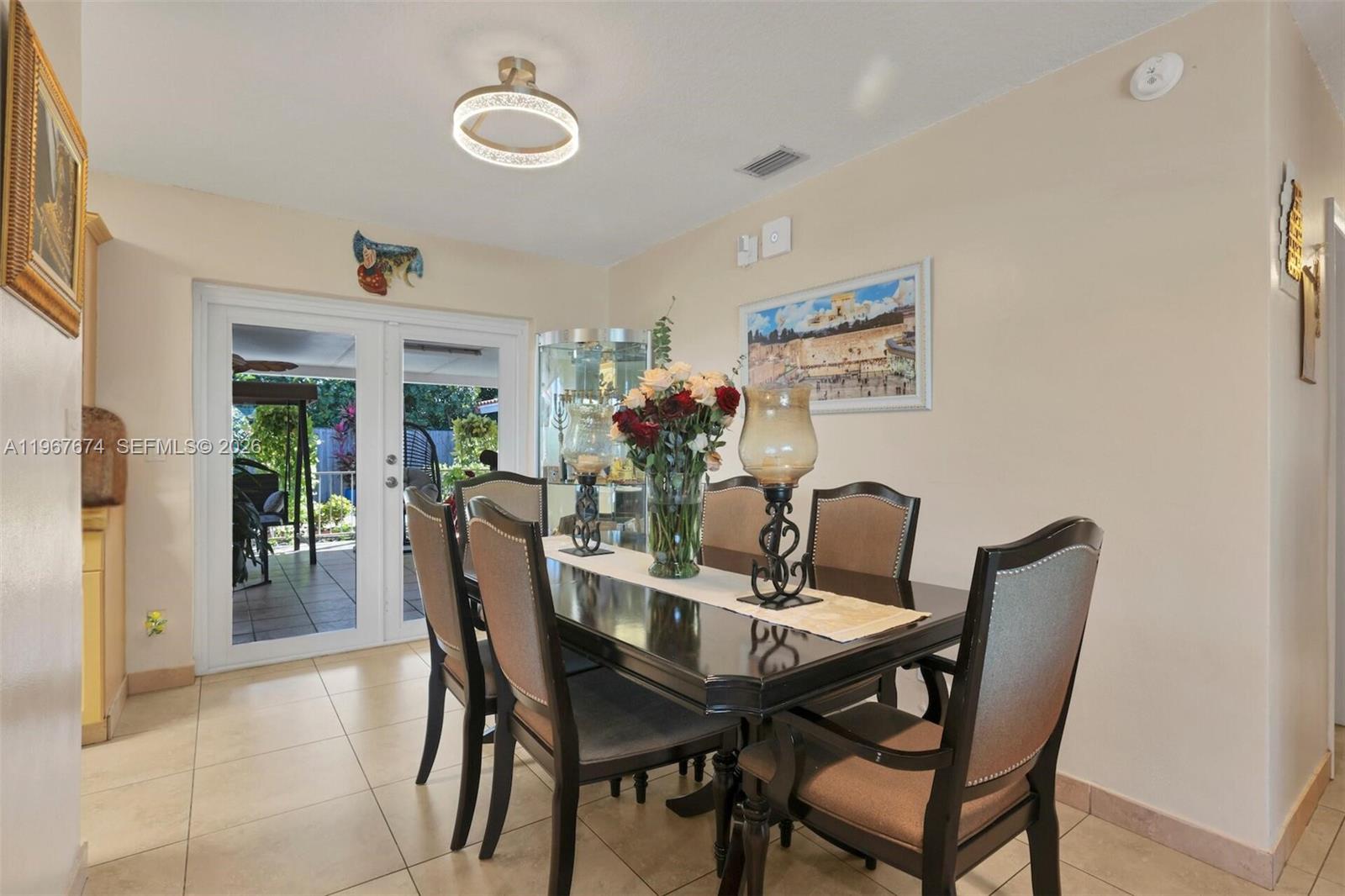 A dining room features a dark wood table, upholstered chairs, and a glass display cabinet — 1901 SW 90th Ave, Miami FL 33165, MIAMI, FL