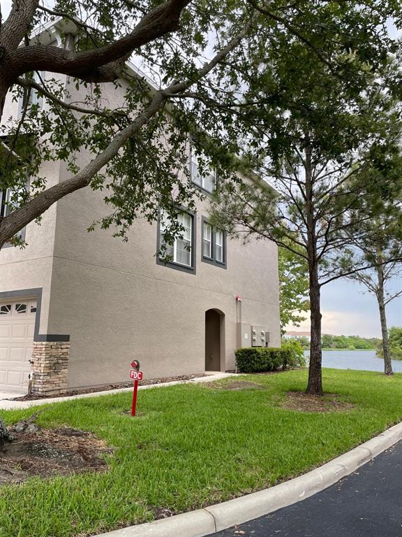 Exterior view of a multi-story tan stucco building with a garage and a fire department connection — 2401 LEXINGTON OAK DRIVE, BRANDON, FL