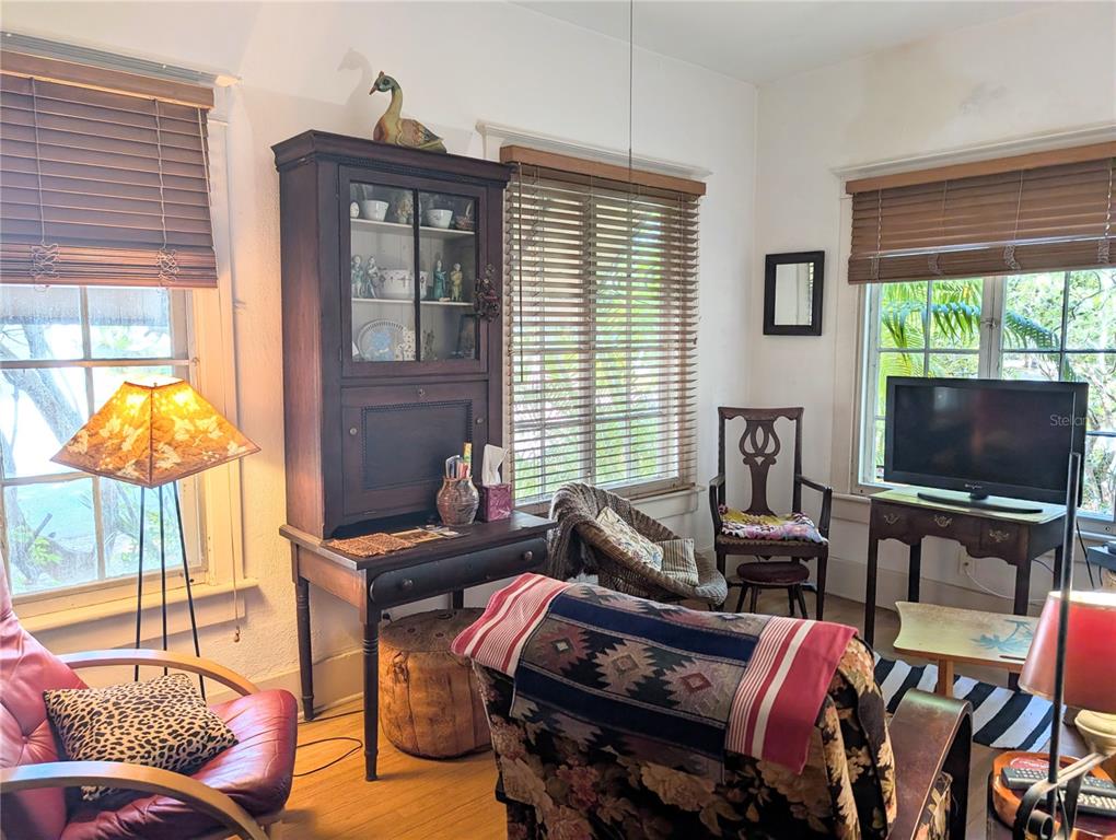 A living room features a dark wood hutch, a television, and several chairs with patterned cushions — 1701 SIESTA DRIVE, SARASOTA, FL