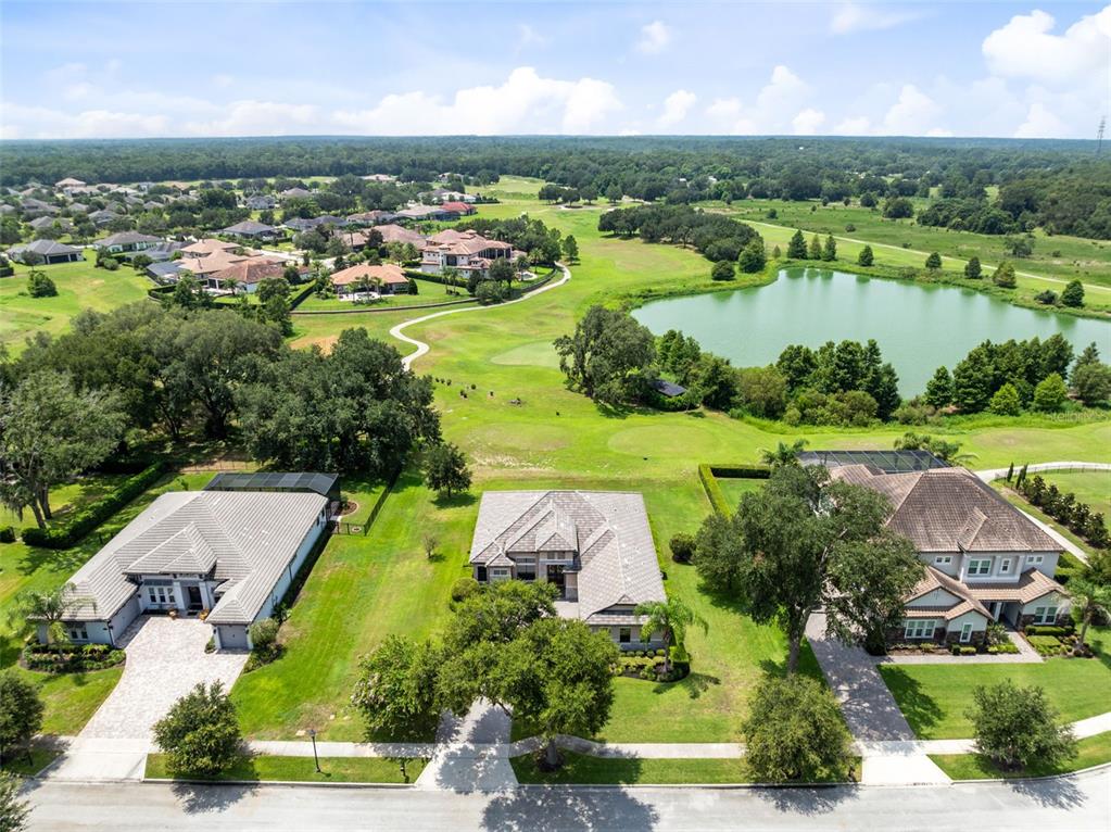 An aerial view shows three suburban houses situated along a street next to a golf course — 25858 CROSSINGS BLUFF LANE, SORRENTO, FL
