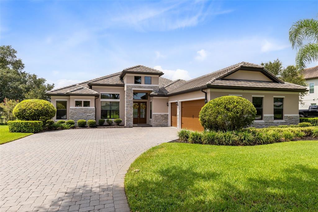 A single-story house features a stone facade, a tiled roof, and a paved driveway — 25858 CROSSINGS BLUFF LANE, SORRENTO, FL