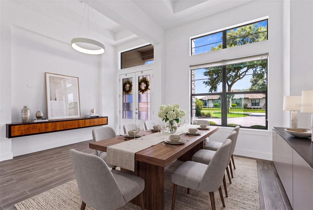 A modern dining room features a wooden table, gray chairs, and large windows with views — 25858 CROSSINGS BLUFF LANE, SORRENTO, FL