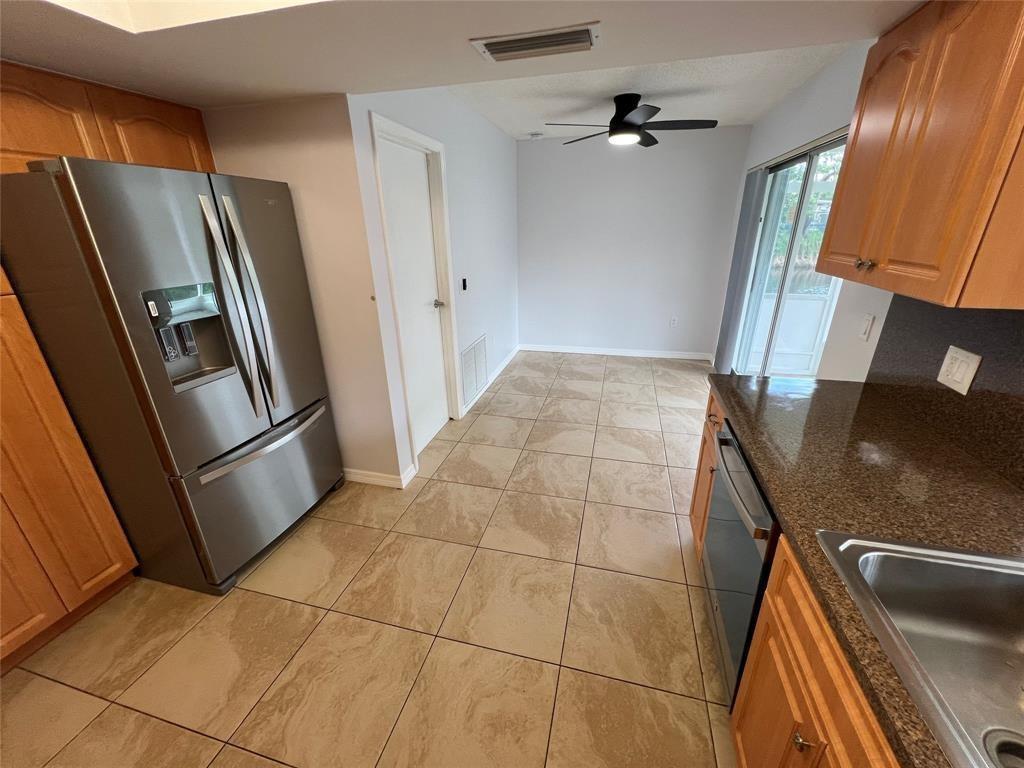 A kitchen features stainless steel appliances, wood cabinets, granite countertops, and light-colored tile flooring — 2650 NW 94th Way, Sunrise FL 33322, SUNRISE, FL