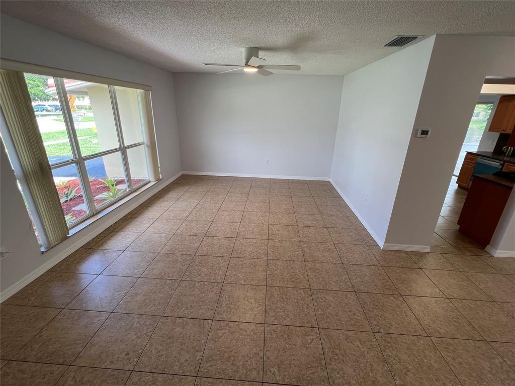 An empty room with tan tile flooring, a ceiling fan, and large windows — 2650 NW 94th Way, Sunrise FL 33322, SUNRISE, FL