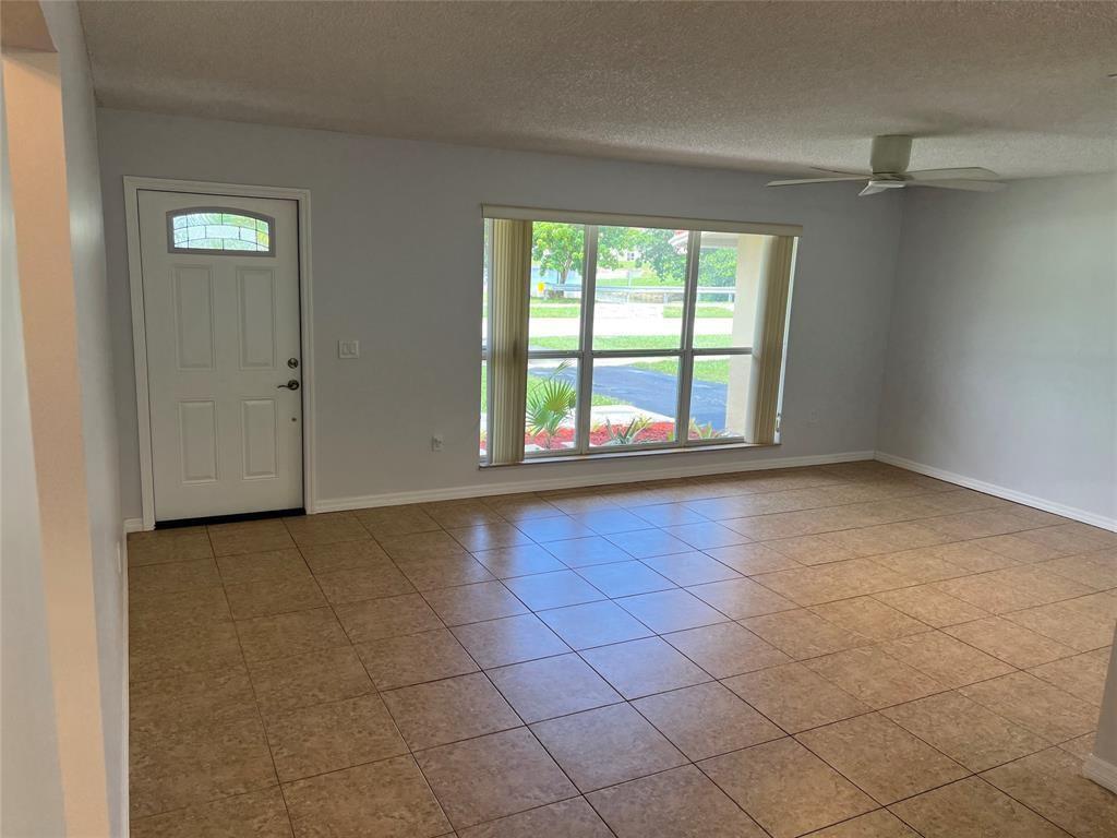 A living room with light gray walls, tan tile flooring, a ceiling fan, and large windows — 2650 NW 94th Way, Sunrise FL 33322, SUNRISE, FL