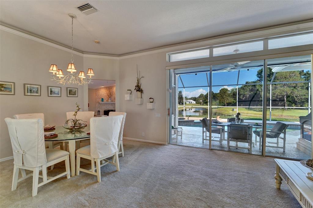 A dining area with a glass table and chairs overlooks a pool and lake view — 740 SALT LAKE DRIVE, TARPON SPRINGS, FL