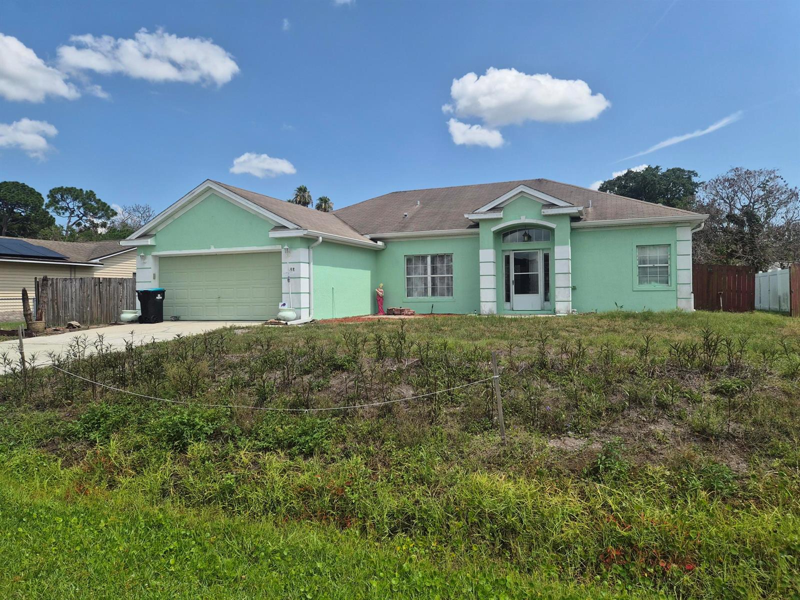 A light green single-story house with a concrete driveway and a two-car garage — 698 Thuringer Street NW, Palm Bay FL 32907, PALM BAY, FL