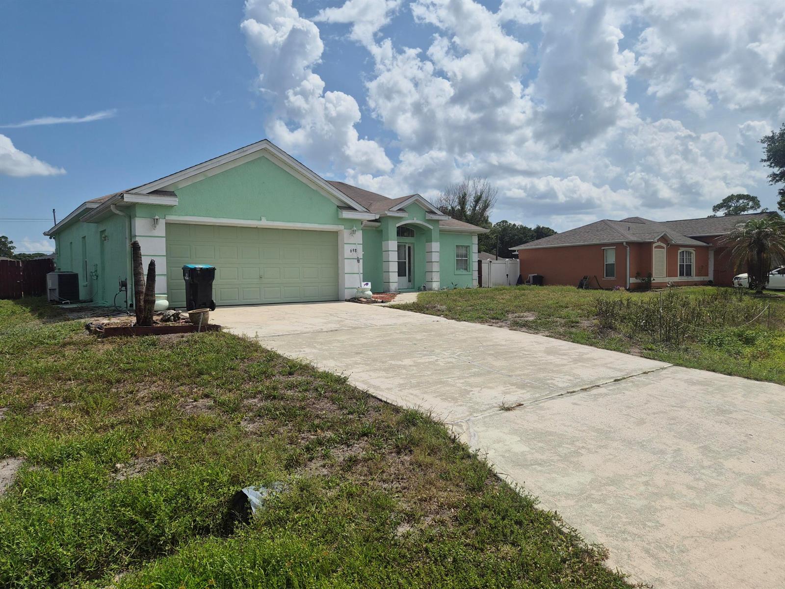 The exterior of a light green house features a metal door, windows, and an AC unit — 698 Thuringer Street NW, Palm Bay FL 32907, PALM BAY, FL