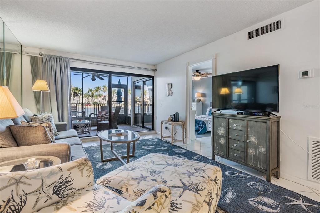 A living room with a coastal-themed rug, a television console, and a view of water — 6294 BAHIA DEL MAR CIRCLE UNIT 107, ST PETERSBURG, FL