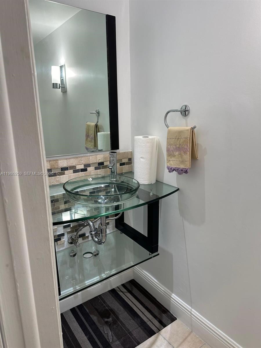 A bathroom features a glass vessel sink, a glass countertop, and a wall-mounted mirror — 8500 SW 109th Ave # 202, Miami FL 33173, MIAMI, FL