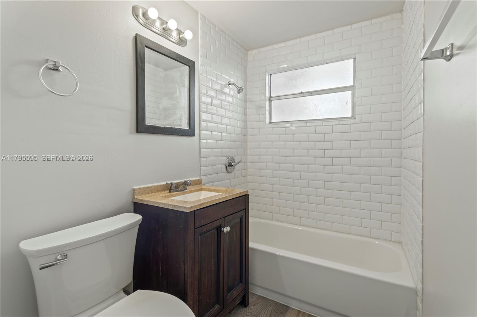 A bathroom features a white toilet, a dark wood vanity, and a white subway-tiled tub — 3121 NE 13th Ave, Pompano Beach FL 33064, POMPANO BEACH, FL