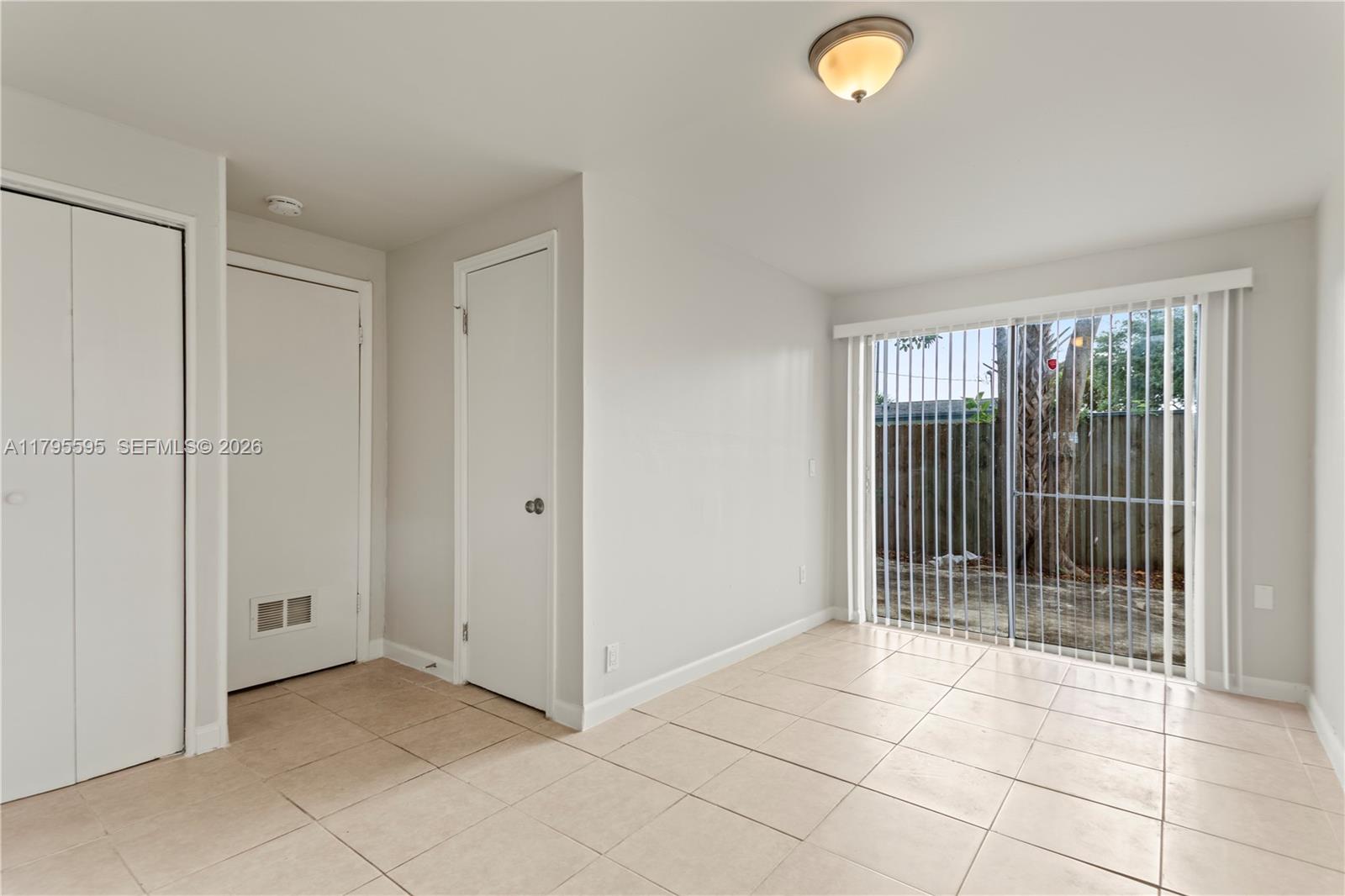A room with beige tile flooring, two white doors, and a sliding glass door — 3121 NE 13th Ave, Pompano Beach FL 33064, POMPANO BEACH, FL